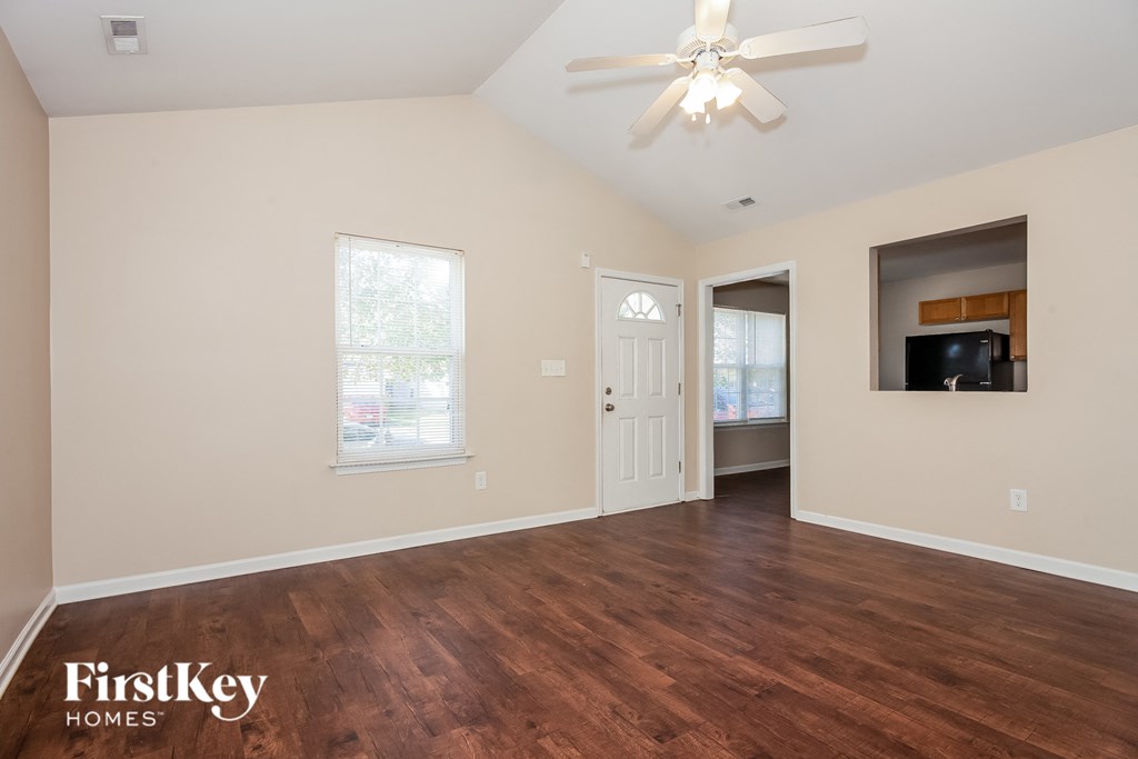 the living room of an empty house with wood flooring and a ceiling fan