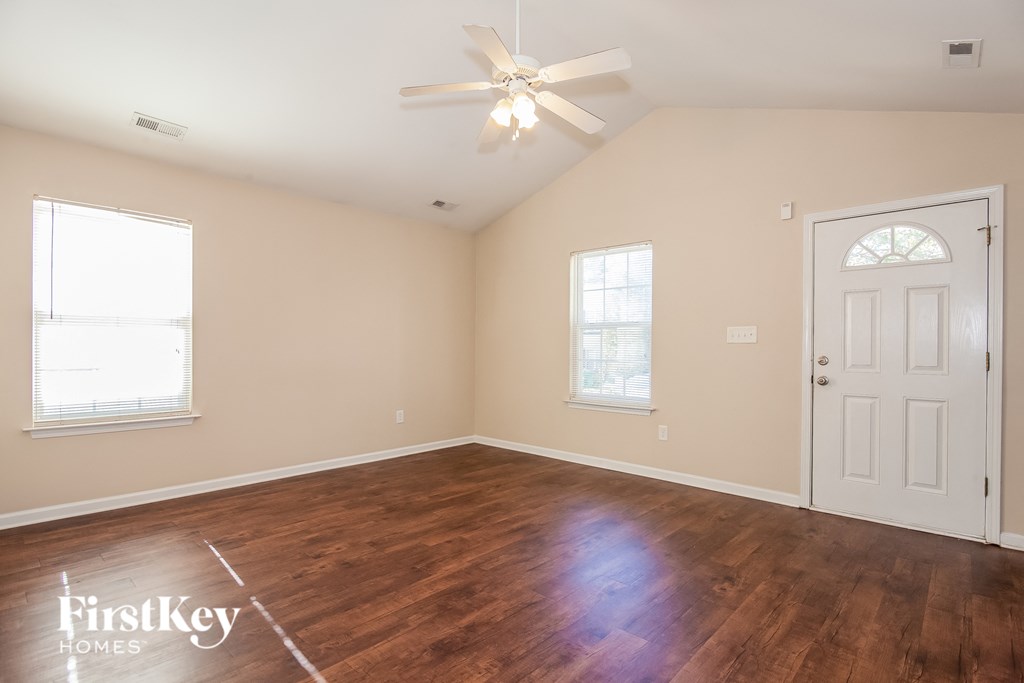 an empty living room with a white door and a ceiling fan