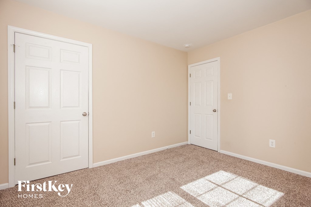 a bedroom with two doors and a carpeted floor