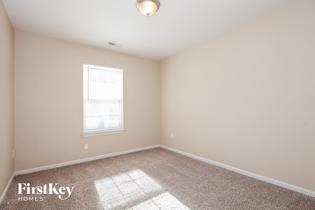 a bedroom with beige carpet and a window