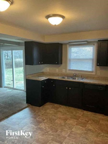 A kitchen with black cabinets and a sink under a window.