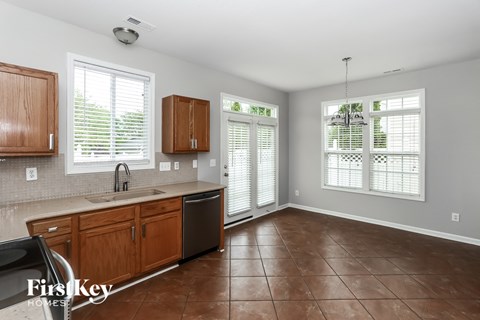 A kitchen with brown cabinets and a black dishwasher.