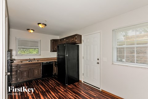 A kitchen with a black fridge and wooden floors.