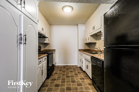 A kitchen with black appliances and white cabinets.