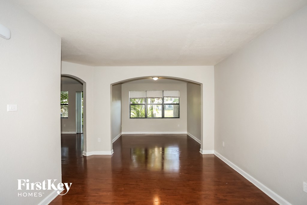 A spacious room with wooden floors and a large window.