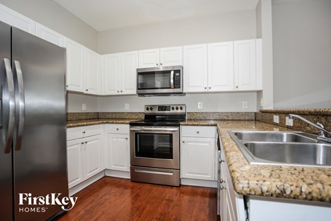 A kitchen with a stainless steel refrigerator and white cabinets.