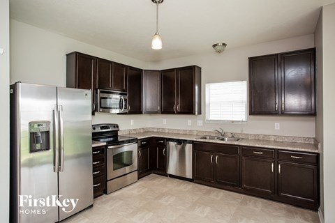 A kitchen with a stainless steel refrigerator and dark brown cabinets.