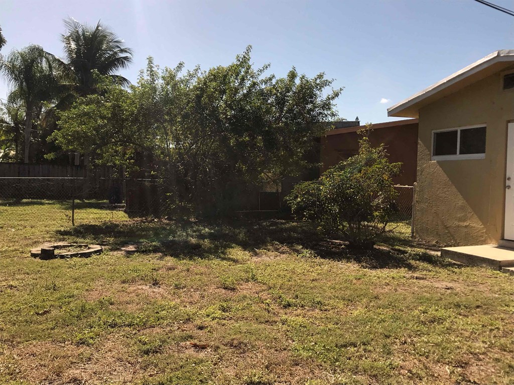A backyard with a house, trees, and a fence.