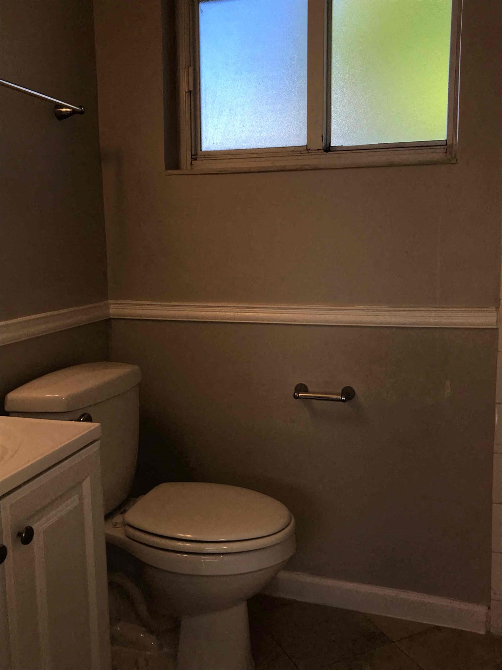 A white toilet sits next to a white cabinet in a bathroom.