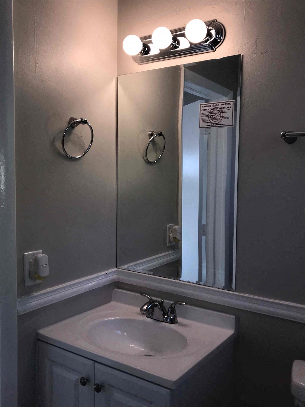 A bathroom with a sink, mirror, and lights.