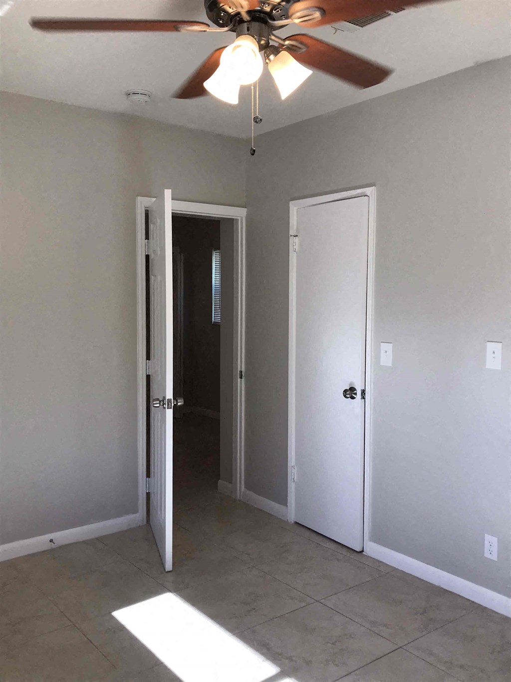 A room with a ceiling fan and two doors.