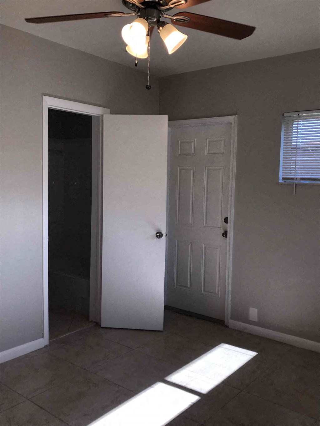 A room with a ceiling fan and a door.