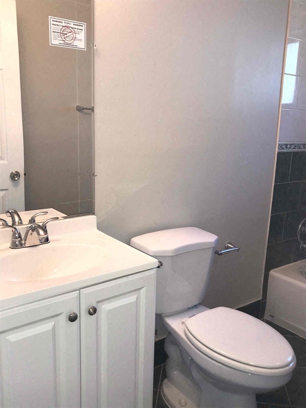 A white toilet in a bathroom with a sink and a cabinet.