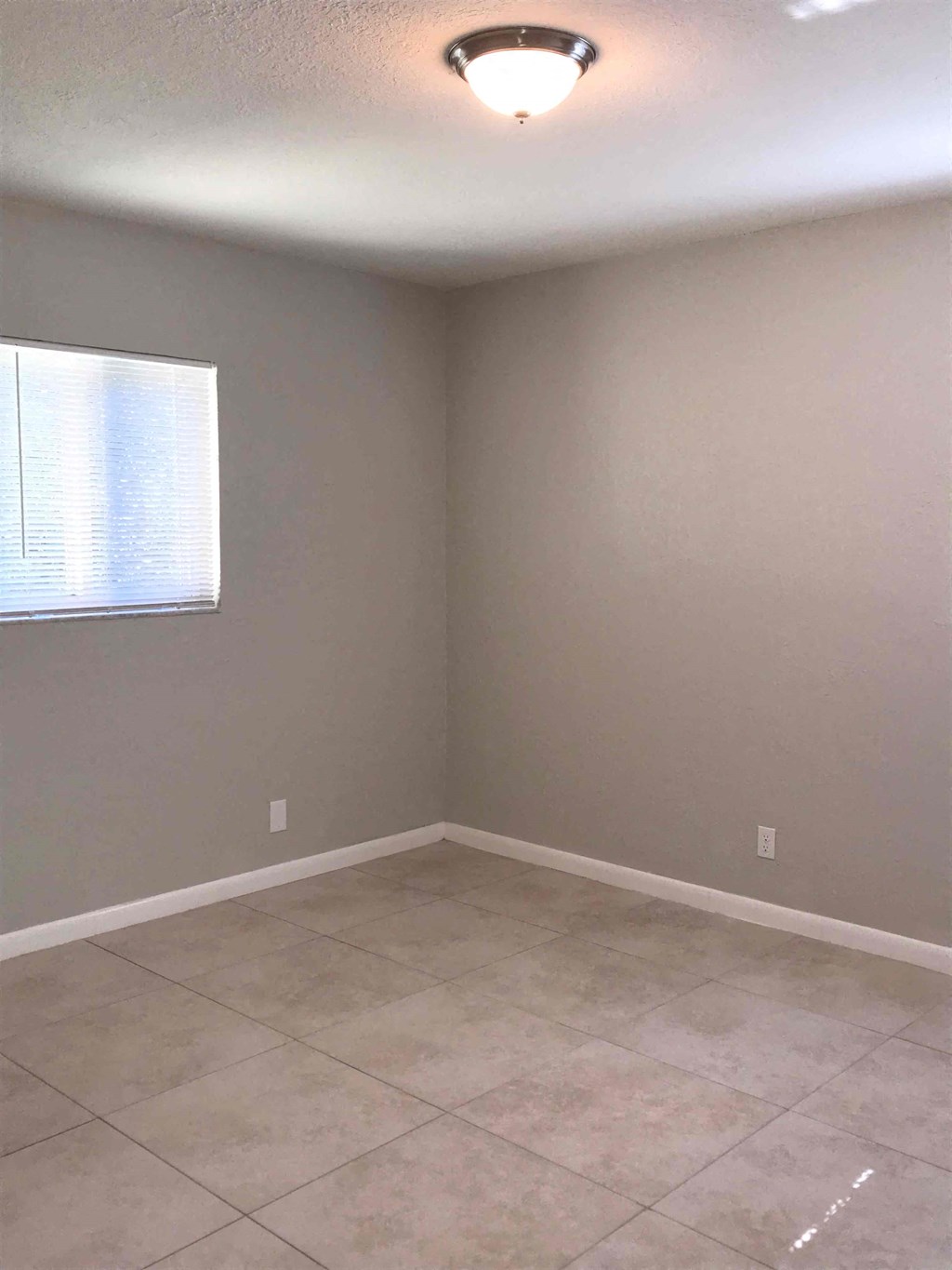 A room with a tiled floor and a window with blinds.