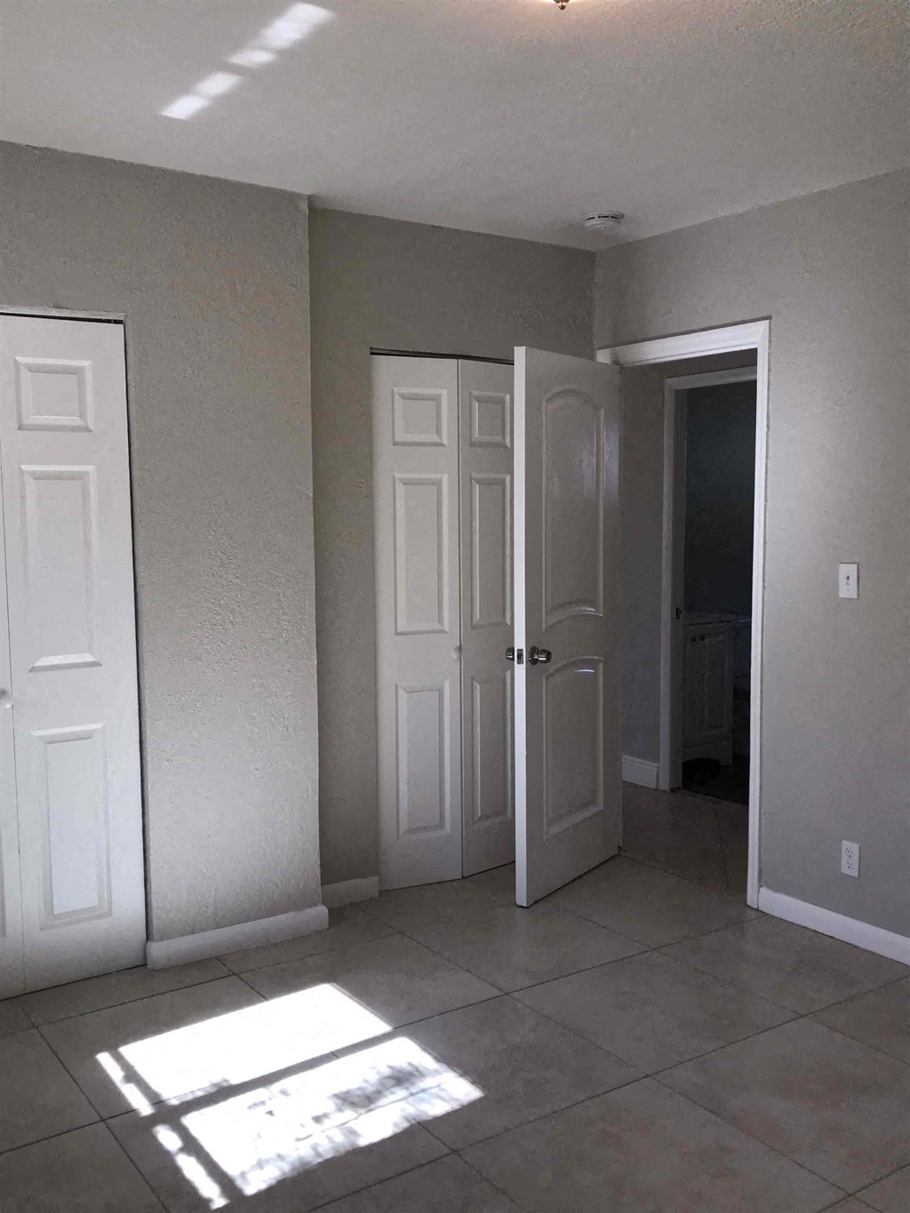 A room with two white doors and a tiled floor.