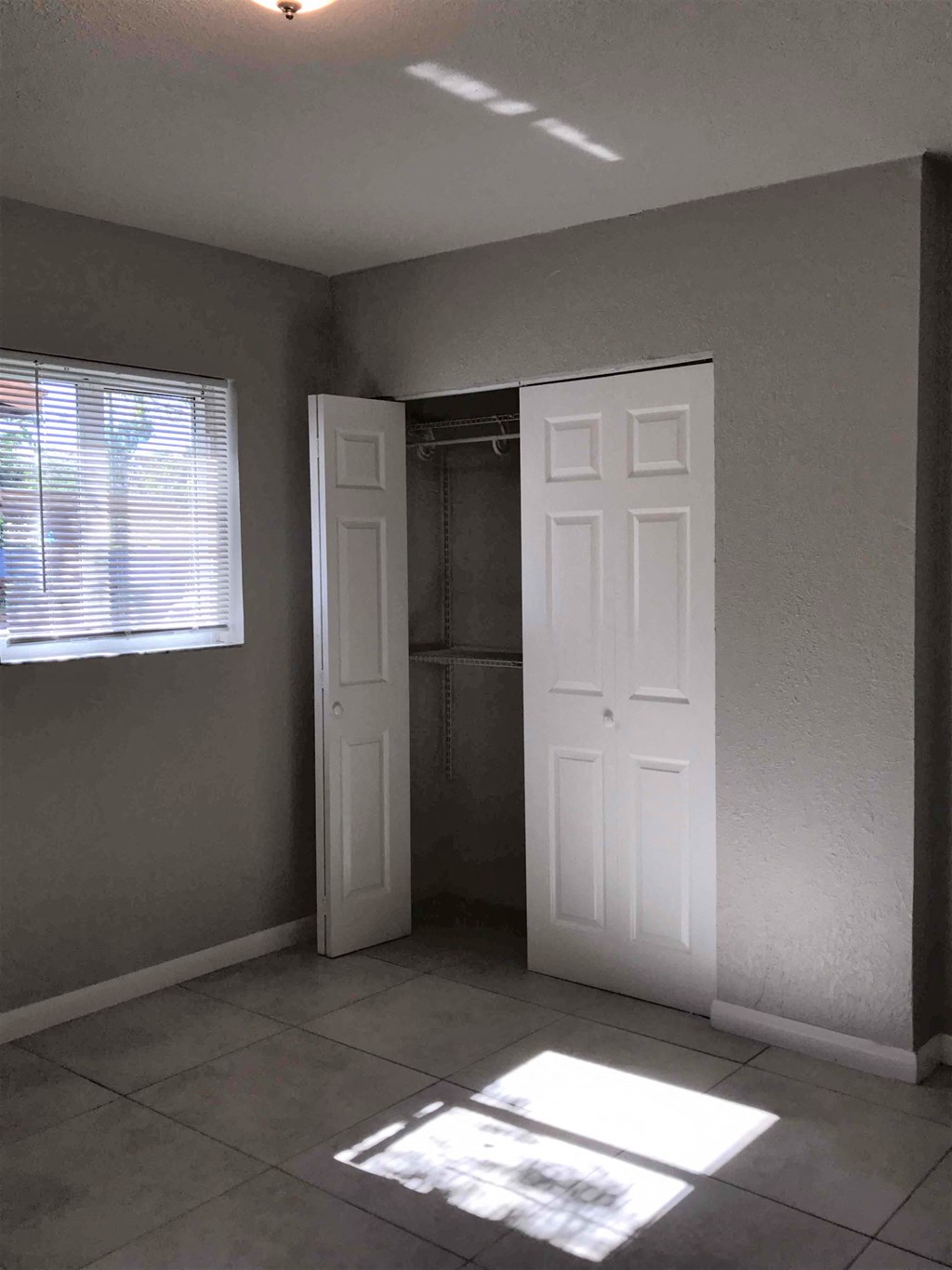 A room with a white door and a window with blinds.