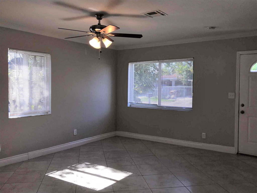 A room with a ceiling fan and two windows.
