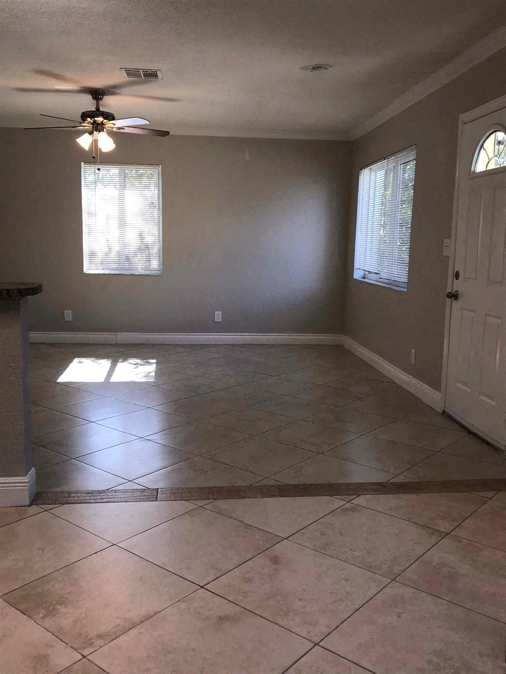 A room with a ceiling fan and tile flooring.