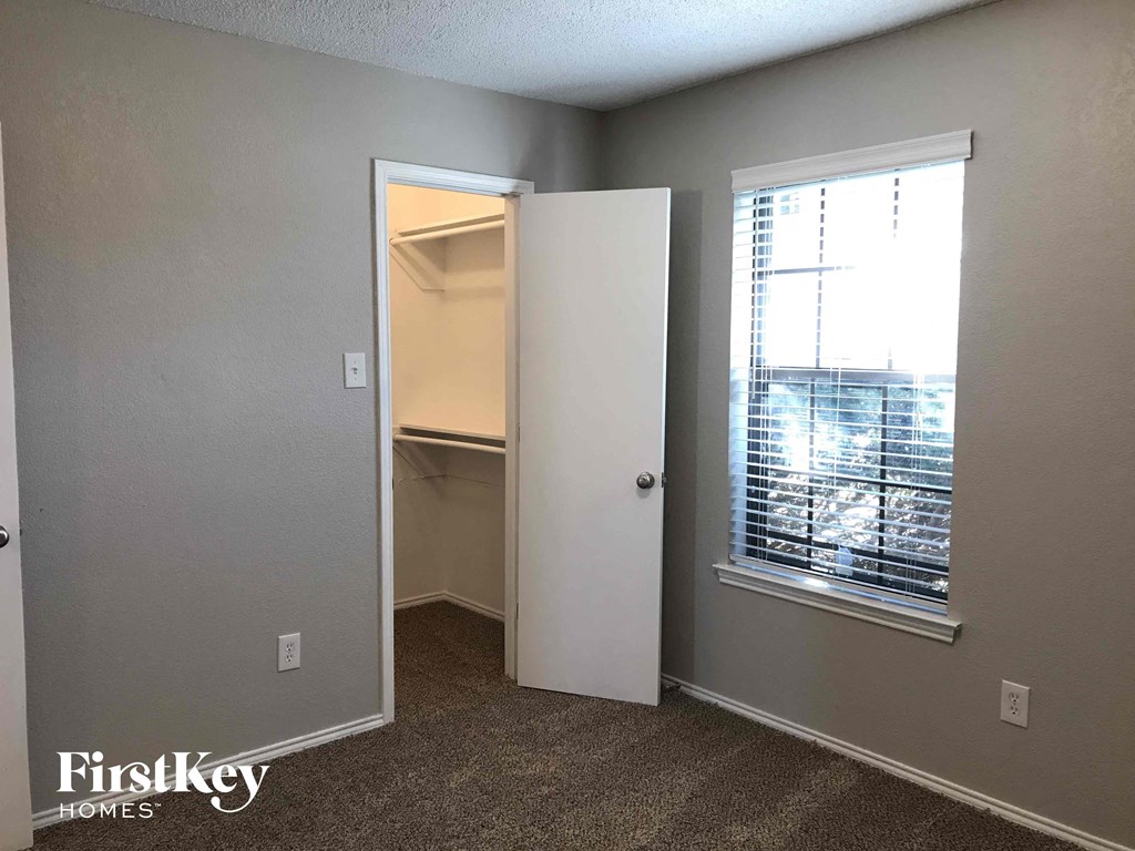a walk in closet in an empty room with a window