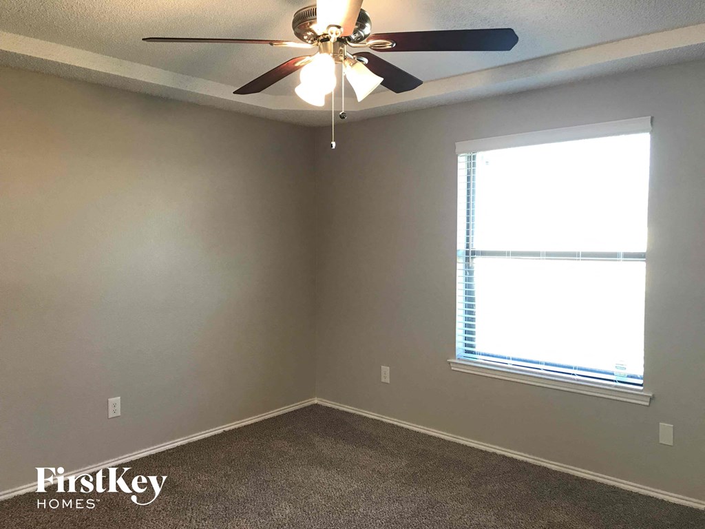 a empty room with a ceiling fan and a window