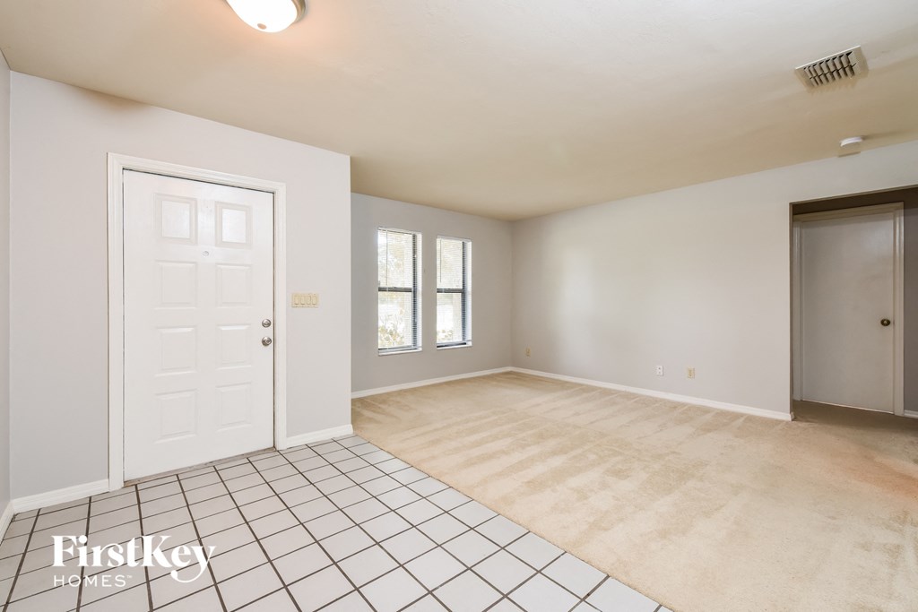 an empty living room with a white door and a tiled floor