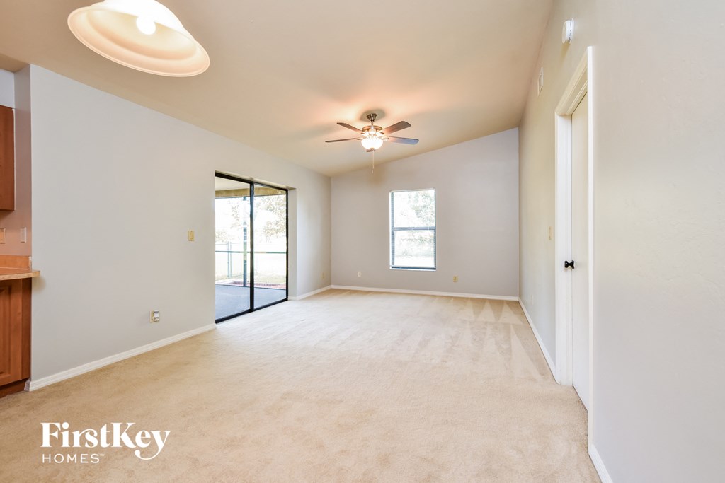 an empty living room with a ceiling fan and a door to a patio