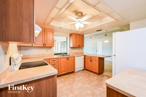 a kitchen with wood cabinets and white appliances and a ceiling fan