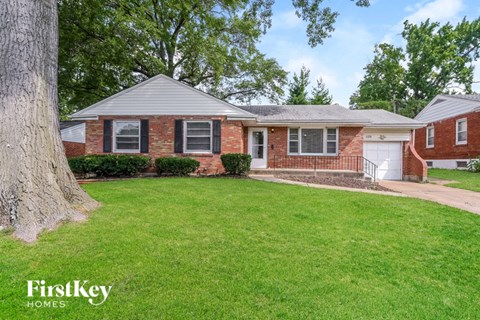 a brick house with a green lawn and a tree