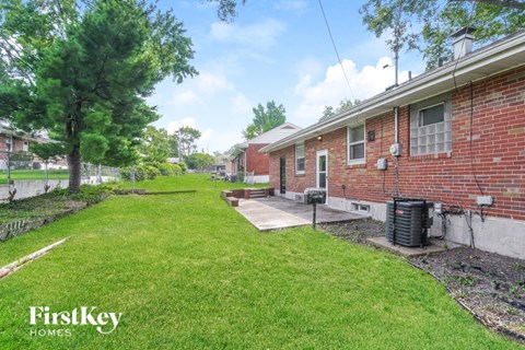 the backyard of a brick house with a yard and grass