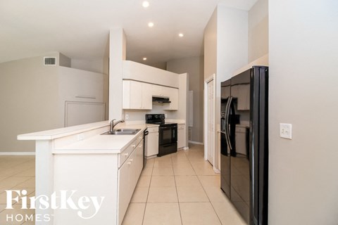A kitchen with a white counter top and a black fridge.