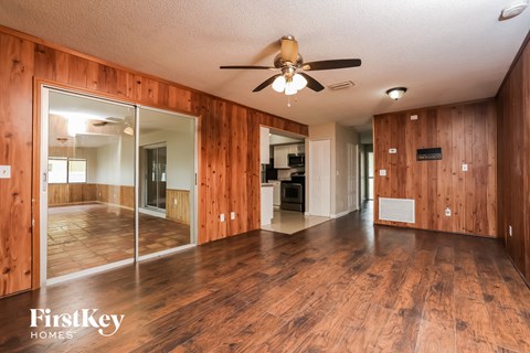 A spacious room with wooden floors and a ceiling fan.
