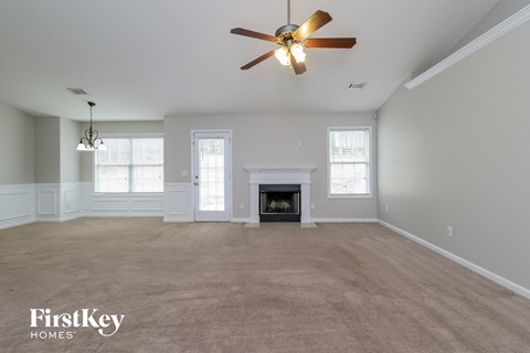A spacious living room with a fireplace and a ceiling fan.