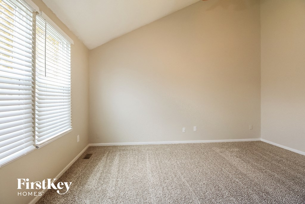 a empty room with a large window and a carpeted floor