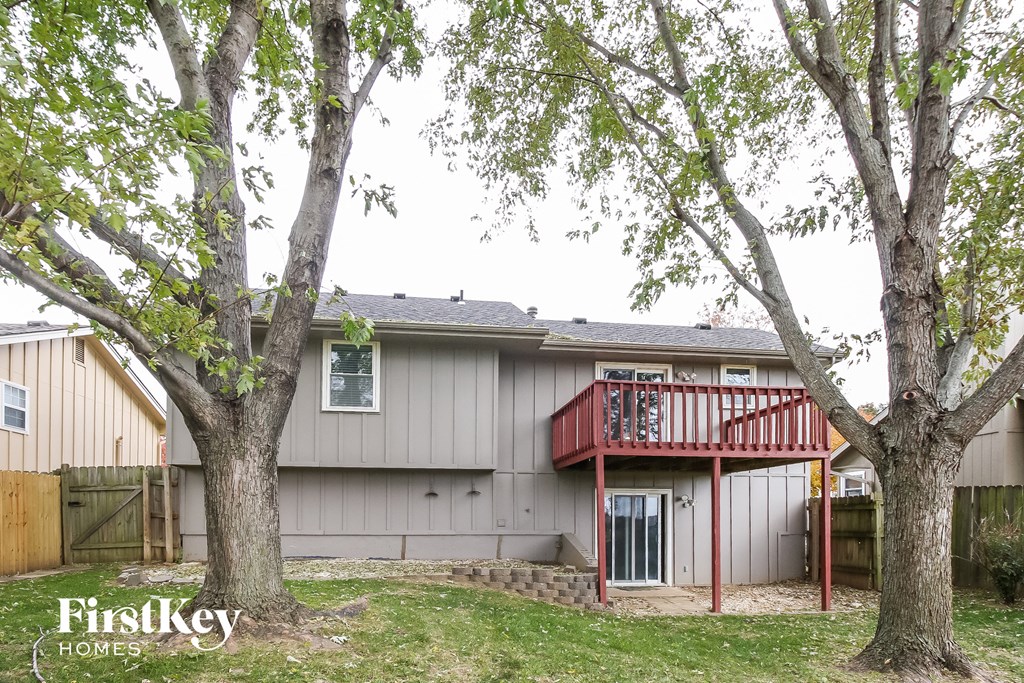 the back of a house with a deck and two trees