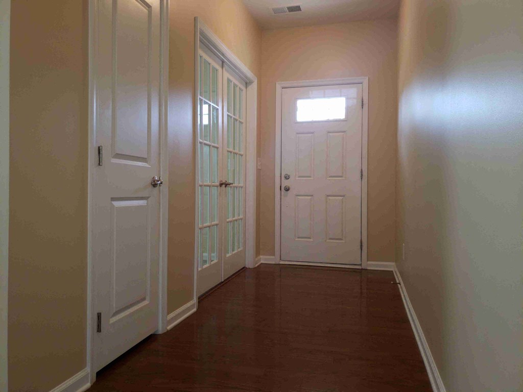 A hallway with white doors and a brown floor.