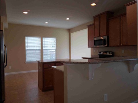 A kitchen with brown cabinets and a black refrigerator.