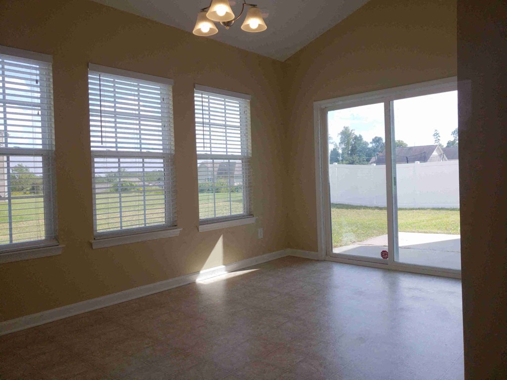 A room with a view of a fence and trees through the windows.