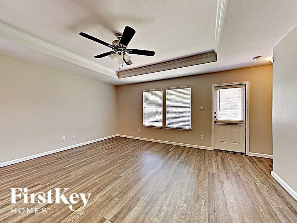 A room with a ceiling fan and wooden flooring.