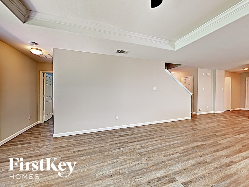 A spacious room with wooden flooring and white walls, branded with "FirstKey Homes".