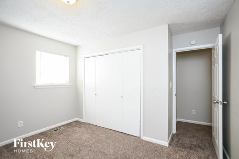 A bedroom with a white closet and a window.