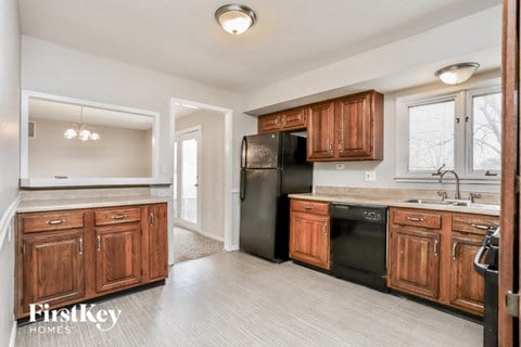 A kitchen with wooden cabinets and a black refrigerator.