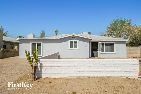 a white house with a white fence and a cactus