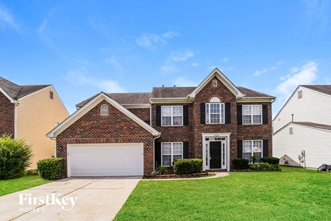 a brick house with a white garage door and a green lawn
