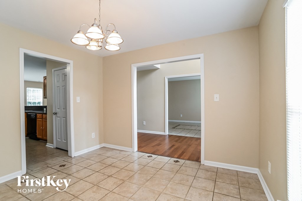 a dining room with a door to the kitchen and a hallway to the living room