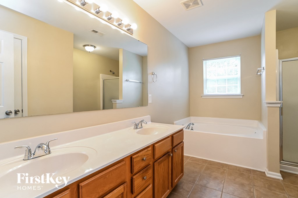 a bathroom with two sinks and a tub and a large mirror