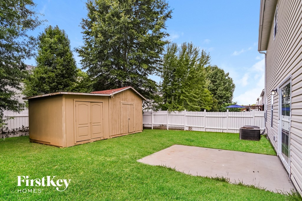 a backyard with a shed and a white fence