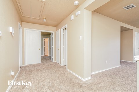 a spacious living room with a carpeted floor and several closets