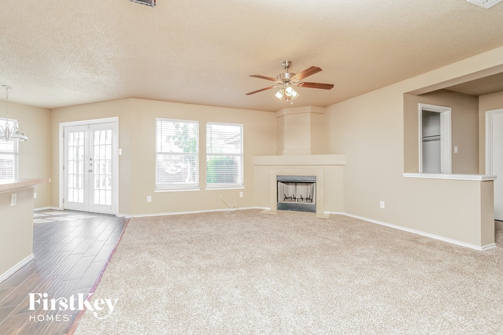 an empty living room with a fireplace and a ceiling fan
