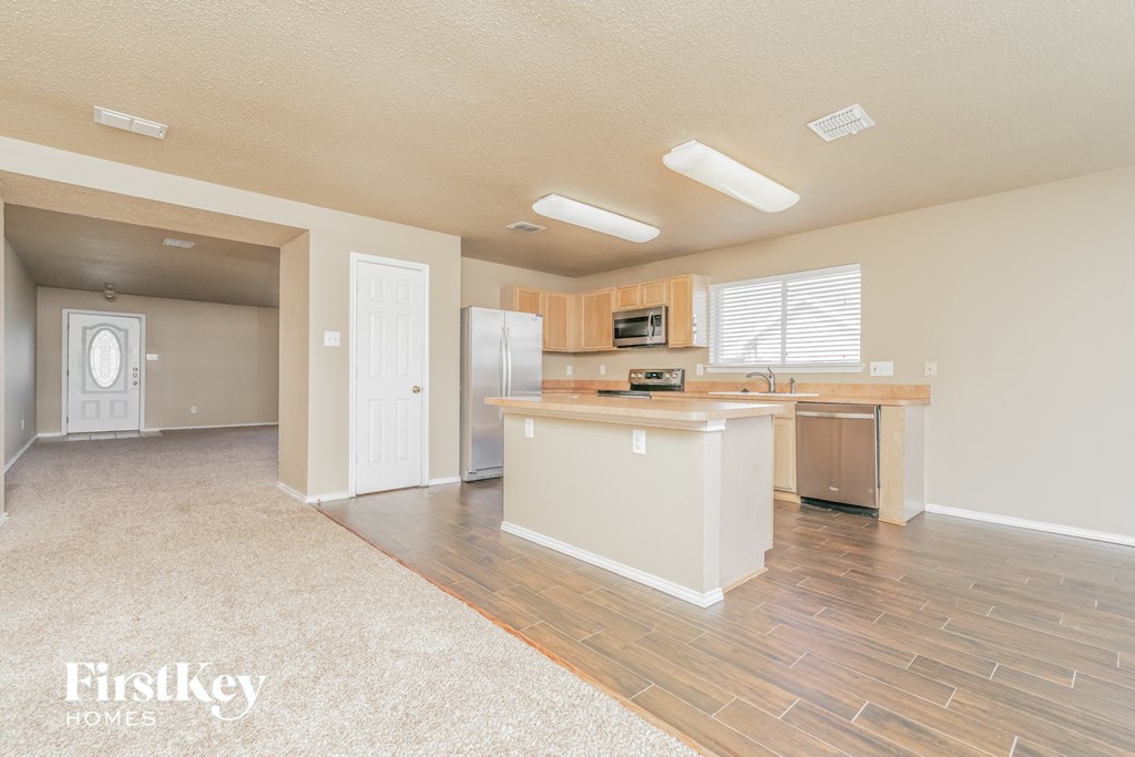 a kitchen and living room with a refrigerator and a sink