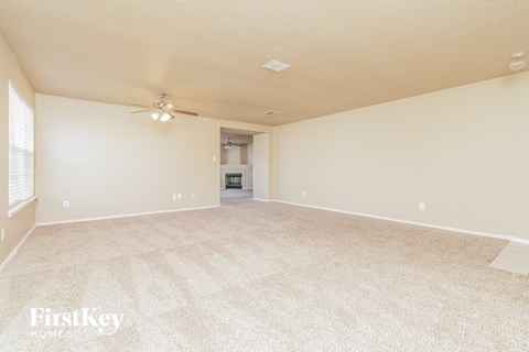 a spacious living room with carpet and a ceiling fan